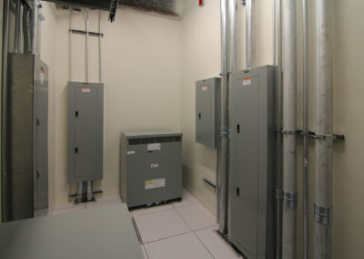 Electrical installation showcasing gray panels and conduits by Kazar’s Electric, Inc., highlighting industrial efficiency.