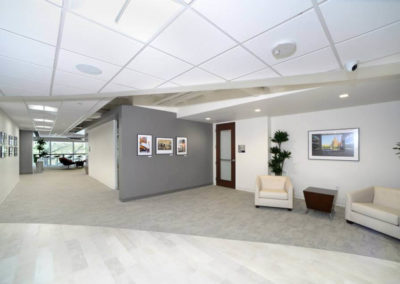 Modern office reception with two armchairs, side table, and large windows, highlighting Kazar's Electric's design commitment.