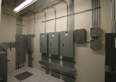 Electrical panel installation by Kazar’s Electric, featuring circuit breakers and metal conduits in a utility room.
