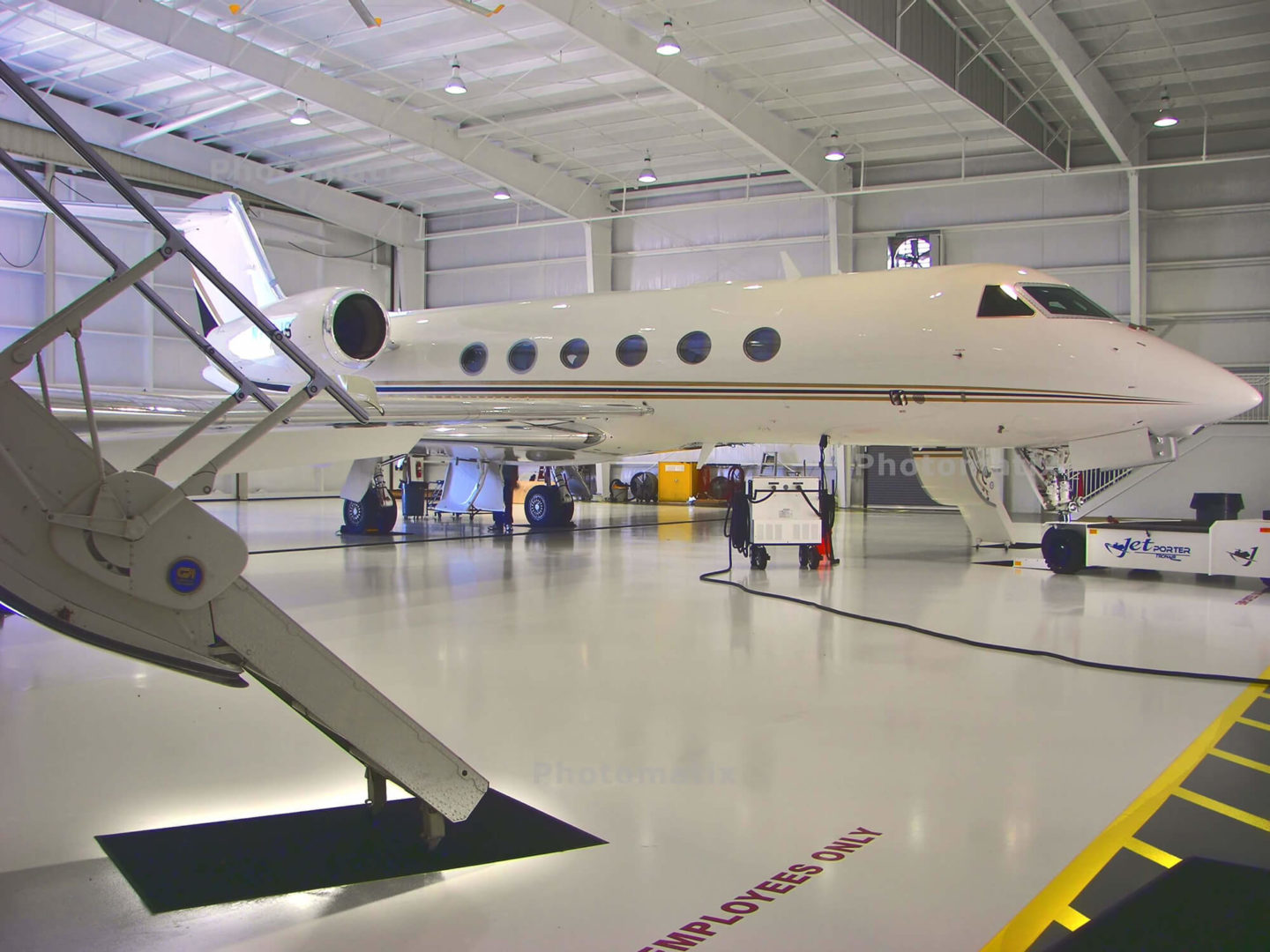 Private jet in a hangar with maintenance equipment, showcasing Kazar's Electric's expertise in commercial electrical services for aviation facilities.