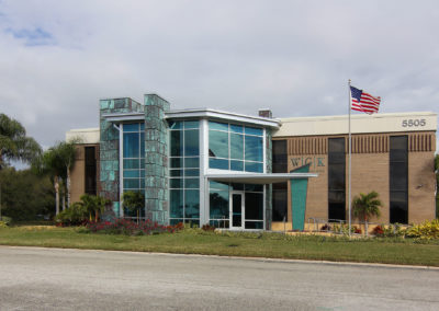 Modern building showcasing Kazar’s Electric's work with glass façade, landscaping, and American flag.