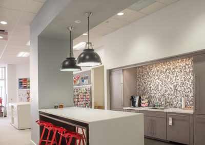 Modern kitchen area with white countertop and red stools, highlighting Kazar’s Electric installation expertise.