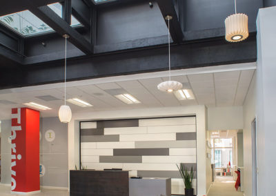 Welcoming reception area of Kazar’s Electric with modern desk, large windows, and 'Thrive' wall art.