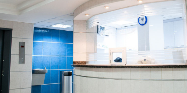 Modern reception area with sleek design, featuring a curved counter, glass partitions, and blue tiled wall, emphasizing aesthetic and functional aspects of commercial electrical work.