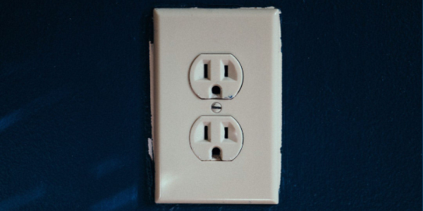 Electrical outlet on a blue wall, illustrating power distribution for safe business environments.