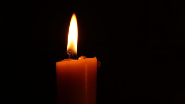 Candle with a flickering flame against a dark background, symbolizing the need for emergency lighting during power outages.