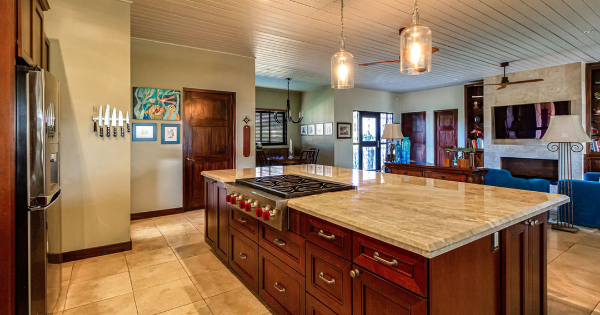 Kitchen interior featuring a central island with a gas stove, wooden cabinetry, and modern lighting, emphasizing a welcoming space for emergency electrical service discussions.