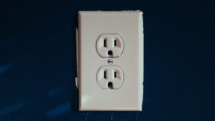 Electrical outlet on a dark blue wall, emphasizing the importance of professional electrical installations for safety in residential projects.