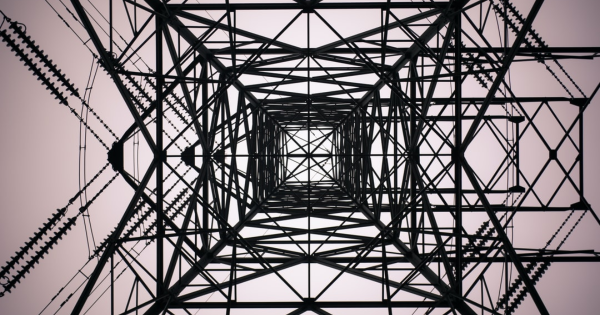 View from below a power transmission tower, showcasing intricate metal lattice structure and electrical components, emphasizing the importance of electrical infrastructure in home safety and functionality.