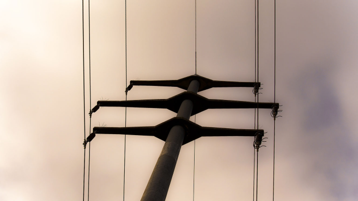 Electrical utility pole with power lines against a cloudy sky, emphasizing the importance of reliable electrical service during emergencies.