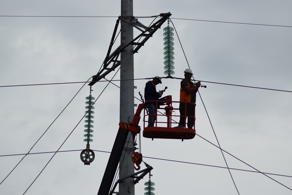 Electricians working on power lines from a lift, emphasizing emergency electrical services during summer outages.