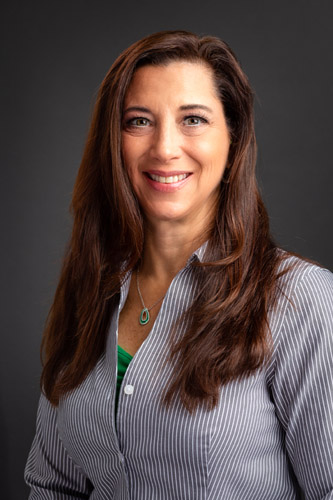 Roiann Kazar of Kazar’s Electric smiling in a striped shirt, exuding professionalism and approachability.