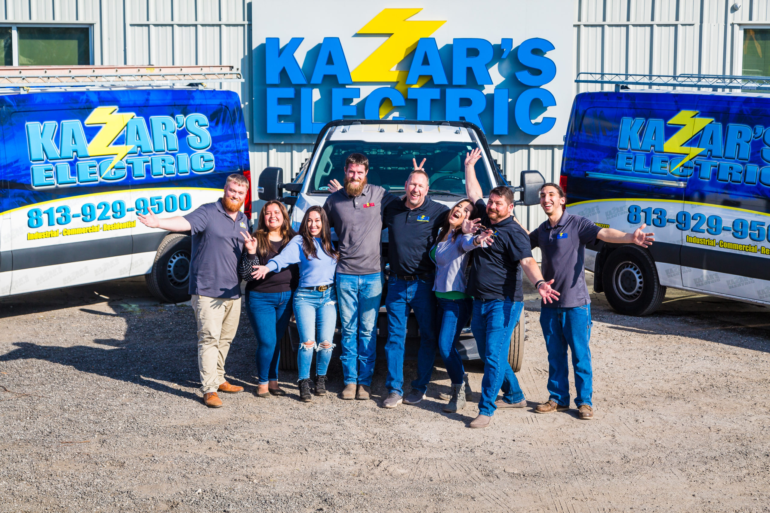 Group of electricians in front of Kazar's Electric vehicles, showcasing teamwork and a positive work environment.