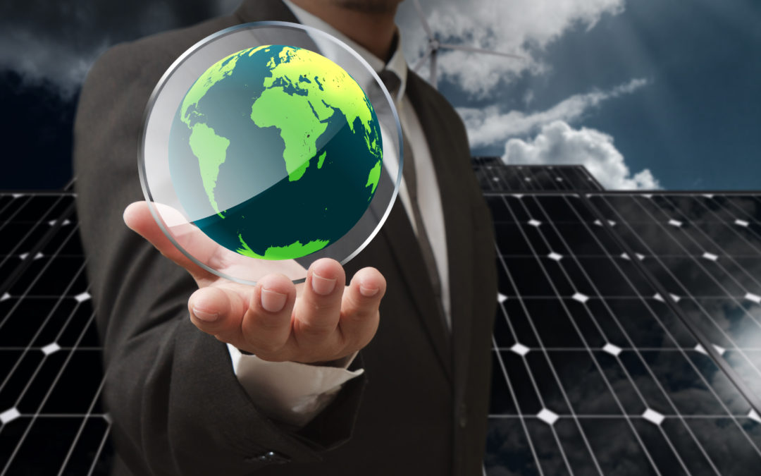 Businessman holding a glass globe representing energy consumption, with solar panels and wind turbines in the background, illustrating the importance of renewable energy in response to increasing global electricity demand.