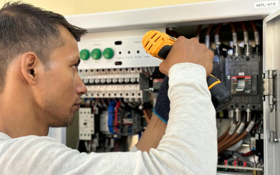 Electrician using a power drill to work on an electrical panel, illustrating Kazar's Electric's expertise in electrical upgrades and maintenance.