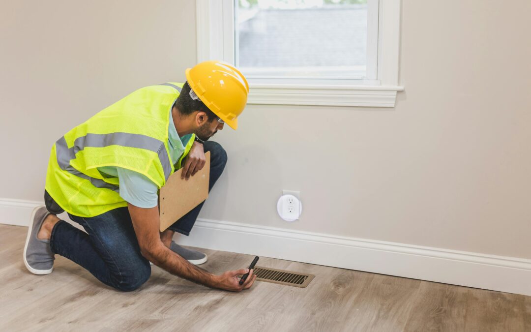 Electrician in safety gear inspecting electrical outlet and vent in residential setting, emphasizing electrical safety and repair services.
