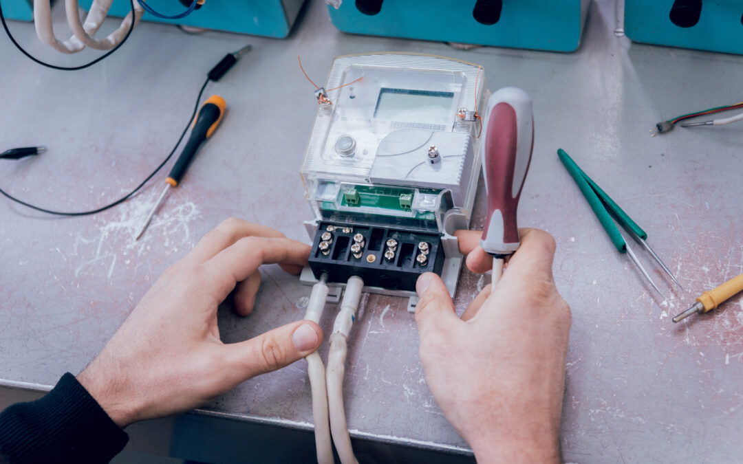 Hands working on an electrical meter with tools, illustrating electrical repair services relevant to Kazar's Electric blog on electrical systems and safety.