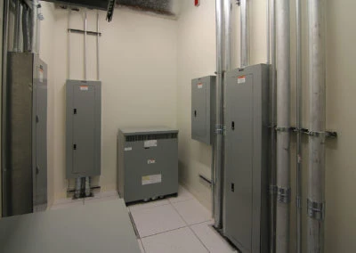 Electrical installation showcasing gray panels and conduits by Kazar’s Electric, Inc., highlighting industrial efficiency.