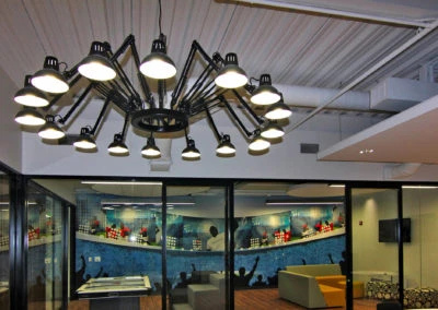 Modern office space by Kazar’s Electric featuring a chandelier, mural, and contemporary furniture for creative collaboration.