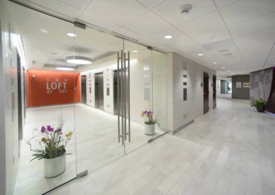 Modern hallway with glass sliding doors and plants, showcasing Kazar’s Electric's architectural projects at "LOFT AT 501.