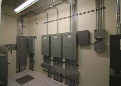 Electrical panel installation by Kazar’s Electric, featuring circuit breakers and metal conduits in a utility room.