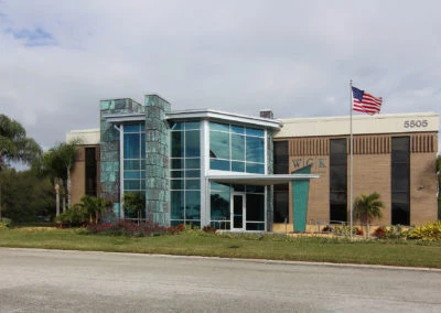 Modern building showcasing Kazar’s Electric's work with glass façade, landscaping, and American flag.