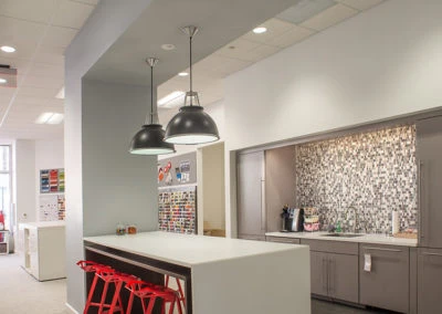 Modern kitchen area with white countertop and red stools, highlighting Kazar’s Electric installation expertise.