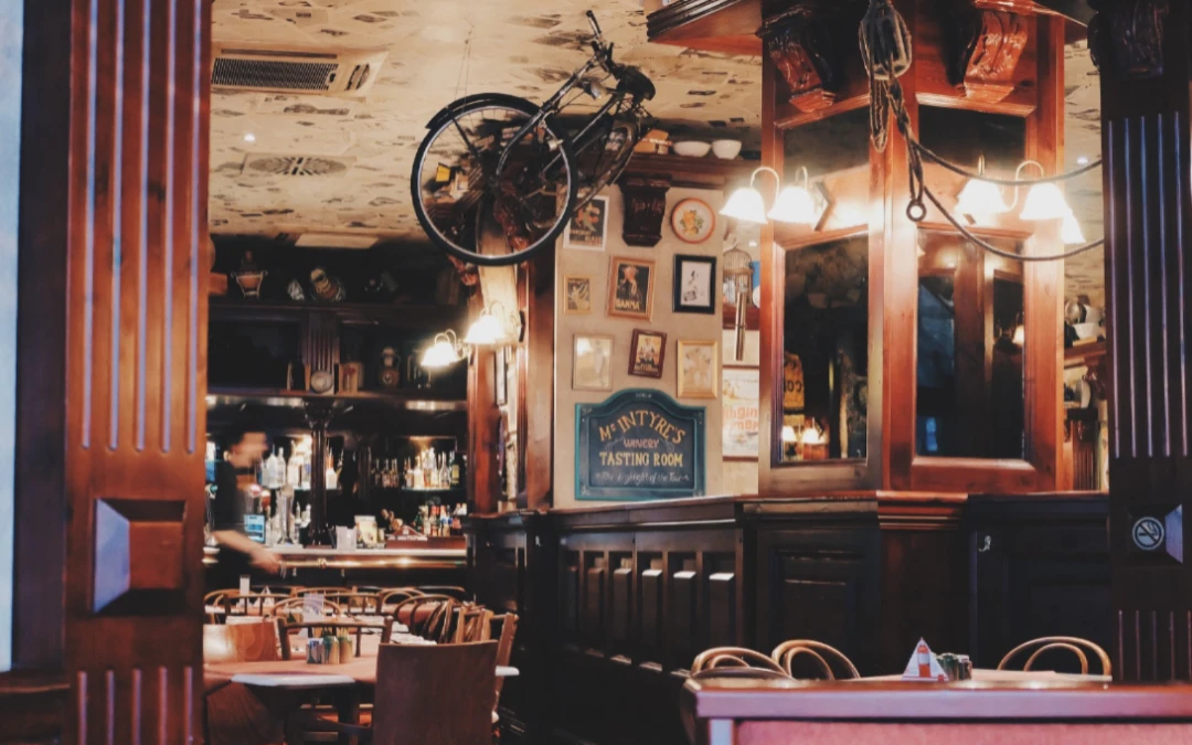 Interior of a restaurant featuring wooden decor, a bicycle hanging from the ceiling, and a bar area with various bottles, emphasizing the need for specialized electrical services for commercial settings.