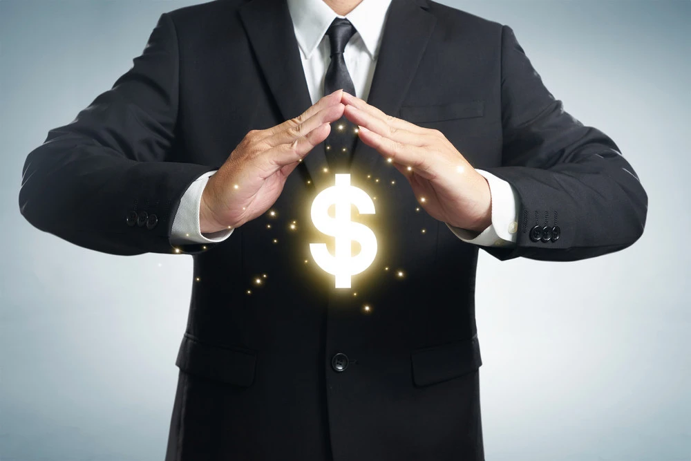 Businessman in suit holding glowing dollar sign, symbolizing energy cost savings and financial efficiency.