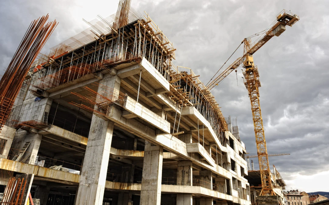 Construction site of a multi-story building with exposed concrete, scaffolding, and a crane, emphasizing energy-efficient design principles.
