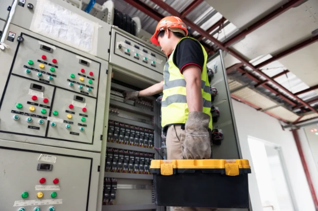 Licensed commercial electrician from Kazar’s Electric inspecting an electrical panel for load balancing in a Tampa business facility.